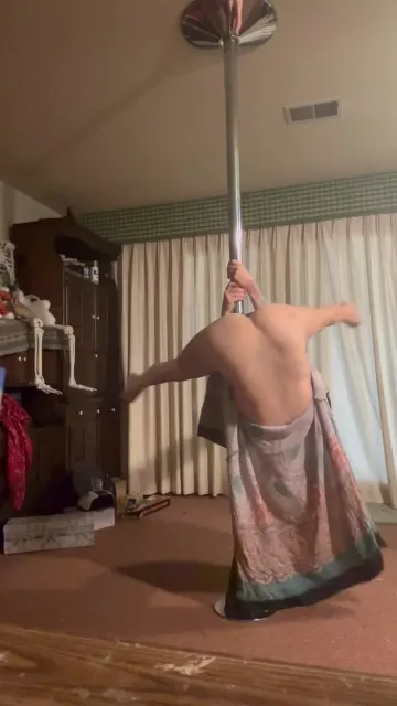 Tattooed Brunette Spins around a Pole in a Patterned Dress
