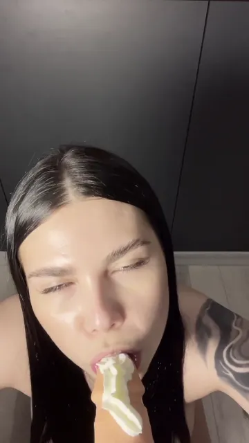 Black-Haired Woman Licks a Toy with White Cream