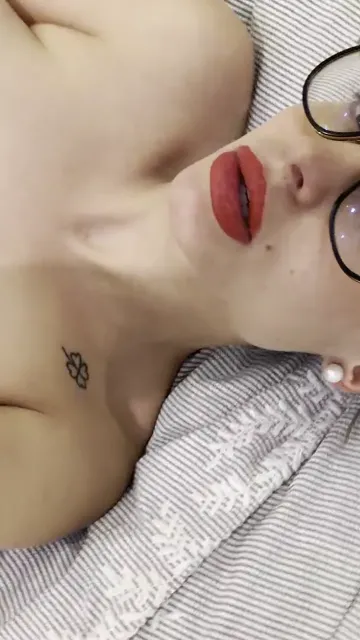 Blonde with Glasses Caresses Her Breasts on a Bed