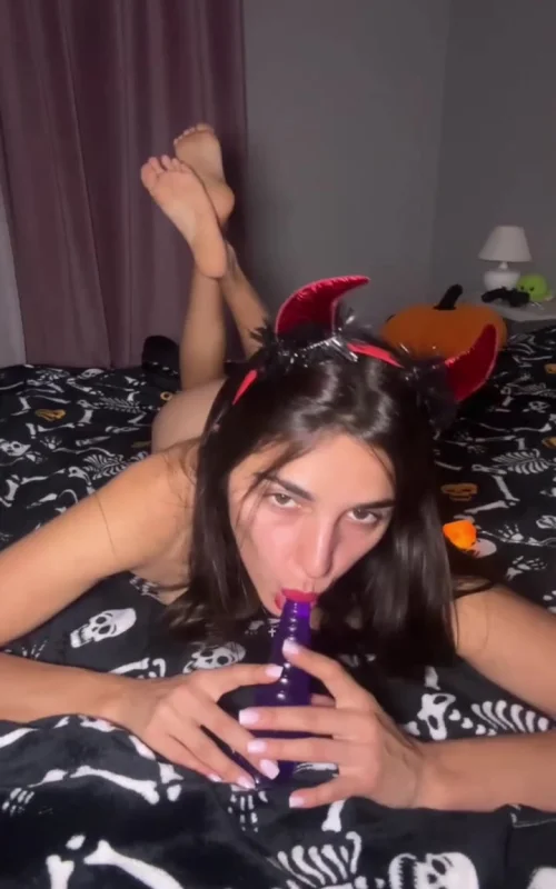 Brunette Holds a Purple Toy on a Patterned Bed